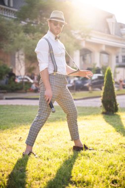 Yakışıklı sunucu ve şovmen şık bir takım elbise ve şapkayla en iyi duygular ve akrobatik hilelerle poz veriyor.