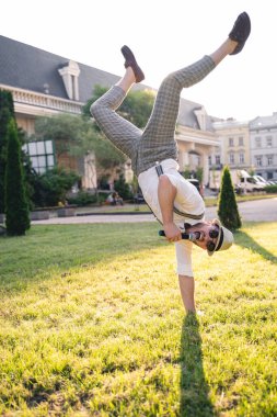Yakışıklı sunucu ve şovmen şık bir takım elbise ve şapkayla en iyi duygular ve akrobatik hilelerle poz veriyor.