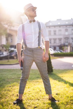 Yakışıklı sunucu ve şovmen şık bir takım elbise ve şapkayla en iyi duygular ve akrobatik hilelerle poz veriyor.