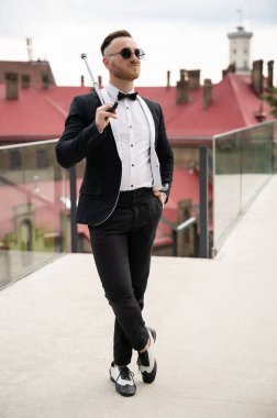 Eski moda giyinmiş, gözlüklü ve bastonlu yakışıklı adam.