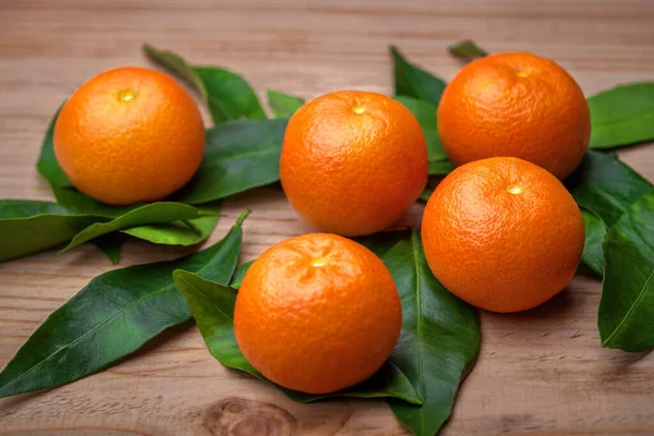 close up of tangerine, orange fruit with leaves on the table