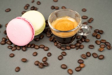 close up of coffee mug scattered coffee beans and  macarons cookies