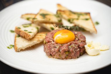 a tasty dish of meat and egg yolk with croutons on a plate