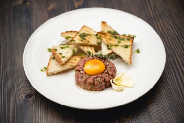 a tasty dish of meat and egg yolk with croutons on a plate
