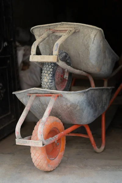 A metal wheelbarrow with one wheel used by workers in construction or gardening
