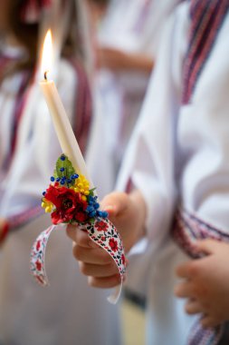 a child holds a candle in his hand in the church during the service