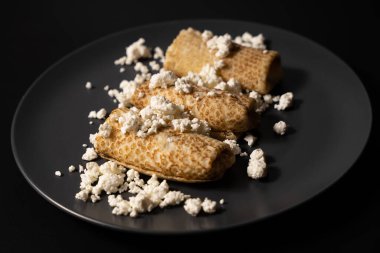 pancakes with cheese on a plate and kitchen utensils on a black background