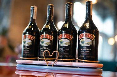 LVIV, UKRAINE - OCTOBER 26, 2022: Baileys Irish Cream four glass bottles on a branded stand with illumination