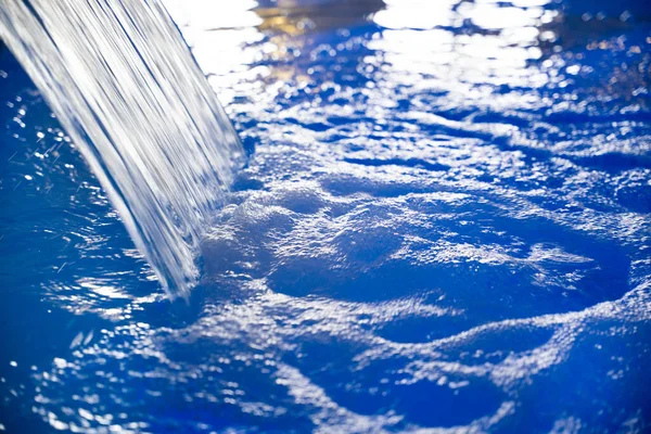 close-up of a waterfall of blue water in an indoor pool