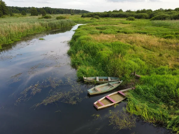 three old boats on a small river moored to the shore, top view