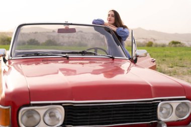 beautiful girl in retro style posing near vintage red cabriolet car
