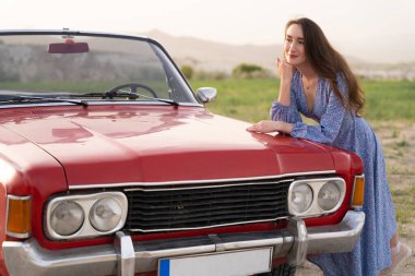 beautiful girl in retro style posing near vintage red cabriolet car