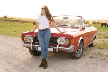 beautiful girl in retro style posing near vintage red cabriolet car