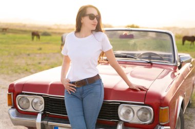 beautiful girl in retro style posing near vintage red cabriolet car
