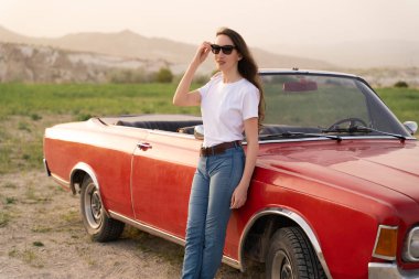 beautiful girl in retro style posing near vintage red cabriolet car