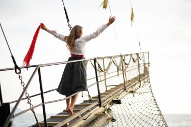 a beautiful girl in a pirate costume on the deck of a ship