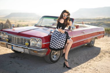 beautiful girl in retro style posing near vintage red cabriolet car