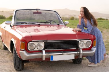 beautiful girl in retro style posing near vintage red cabriolet car