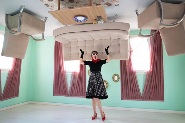 a girl retro style, surprised, in an upside-down house, as well as furniture placed on the up
