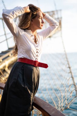 a beautiful girl in a pirate costume on the deck of a ship