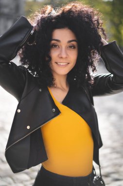 Deri ceketli güzel bir kız şehrin arka planında poz veriyor.