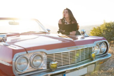beautiful girl in retro style posing near vintage red cabriolet car