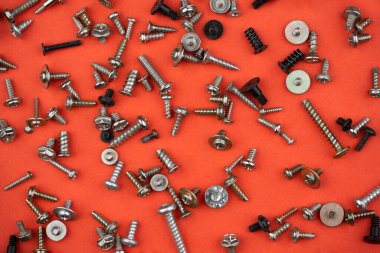 Kırmızı zemine saçılmış bir sürü farklı vida