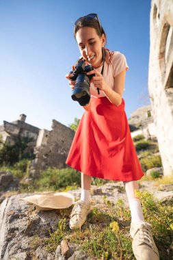 Kameralı kız fotoğrafçı açık havada gülümsüyor.