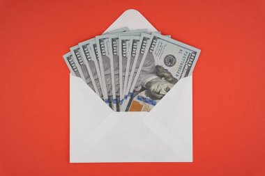 Kırmızı arkaplanda bir zarfın içinde 100 dolarlık banknotlar.