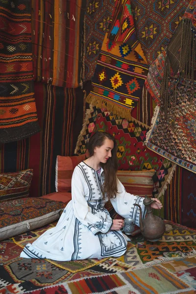 Красивая Девушка Белом Платье Чайником Традиционном Турецком Интерьере Многими Коврами — стоковое фото