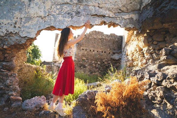 a beautiful girl in a red skirt among the ruins of the old town