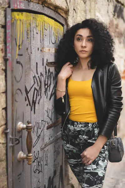 Deri ceketli güzel bir kız şehrin arka planında poz veriyor.