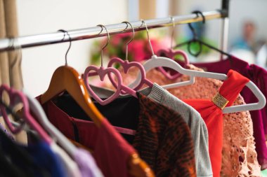 Bir mağazada askılarda birçok farklı renkli kadın kıyafeti var.