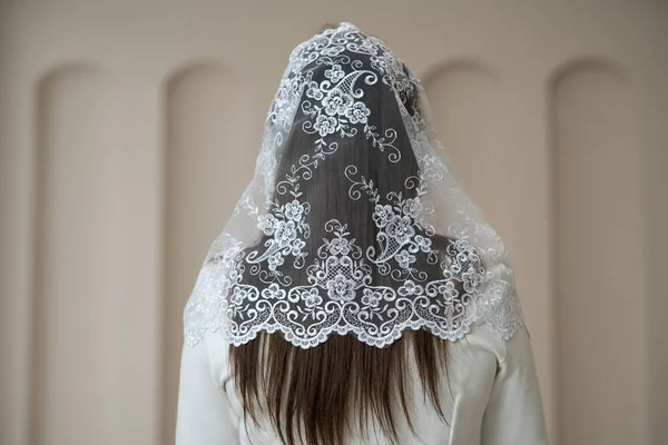 a white wedding veil covers the bride\'s head on her wedding day