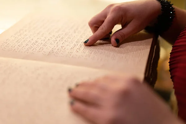close-up of a woman\'s hand reading a braille book