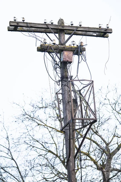 an old electric pole with many broken wires is abandoned