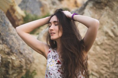 Ellerini açık havada saçlarından tutan güzel bir kızın portresi.