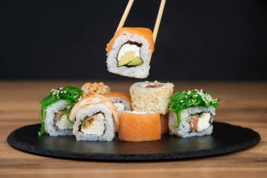 Lezzetli geleneksel Japon suşisi ve çubuk dolu bir tabakta rulo ekmek.