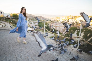 Kapadokya dağlarında güzel ve mutlu bir kız ve bir sürü güvercin.