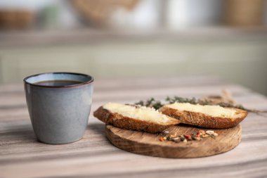 Tahtaya tereyağı sürülmüş bir sandviç ve bir fincan kahve.