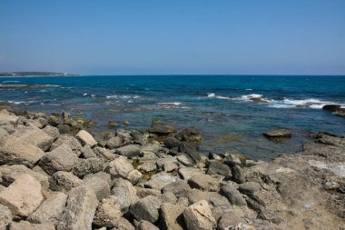 Sahilin güzel manzarası ve mavi gökyüzünün arka planında deniz dalgaları.