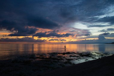Gün batımında deniz sahilinde yürüyen çocuk silueti.