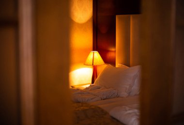 Bir otel odasındaki yatağın başucundaki lambanın güzel bir fotoğrafı.