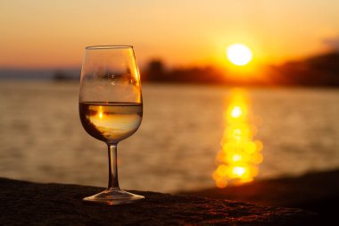 Gün batımında deniz kıyısında bir bardak içki.