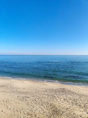 Sahilin güzel manzarası ve mavi gökyüzünün arka planında deniz dalgaları.