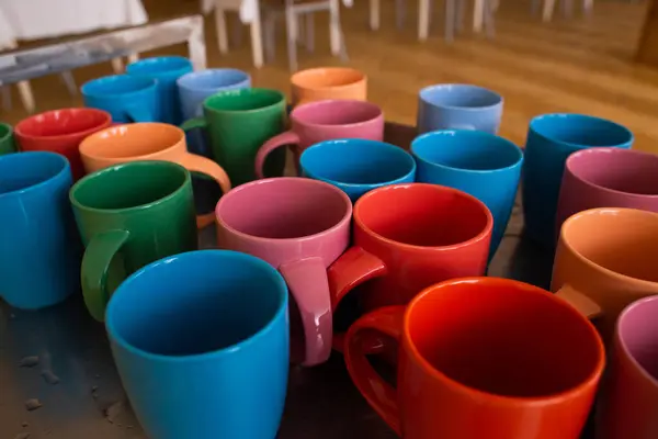 Yemek odasındaki masada bir sürü renkli fincan var.