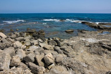 Sahilin güzel manzarası ve mavi gökyüzünün arka planında deniz dalgaları.