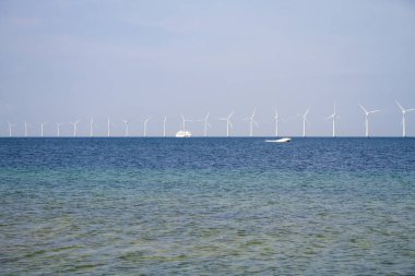 Denizde duran birçok yel değirmeni elektrik üretir.