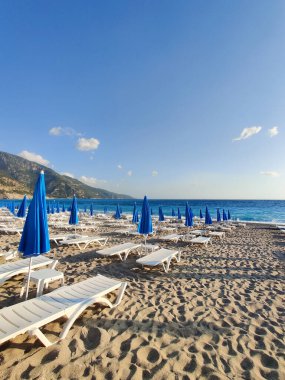 Yazın deniz sahilinde güverte sandalyeleri ve şemsiyeler.