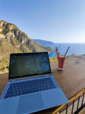 Deniz manzaralı bir masada serbest çalışan birinin bilgisayarı.